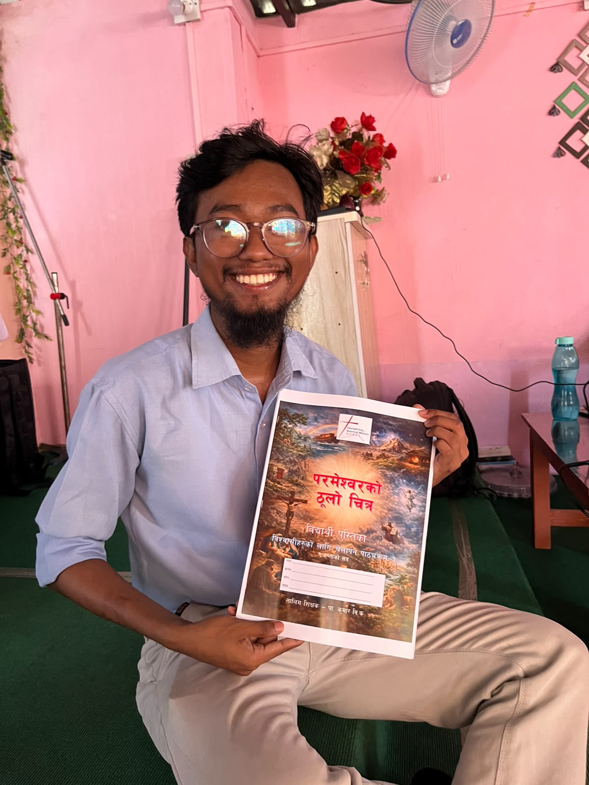 Nepali participant smiling while holding a Nepali Bible-training workbook